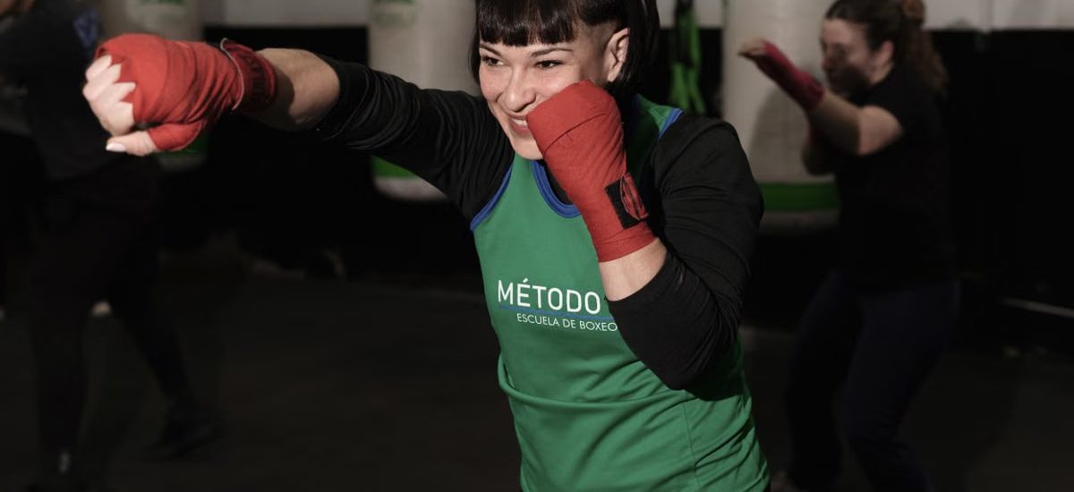 Energetic woman practicing boxing in a Buenos Aires gym with classmates.