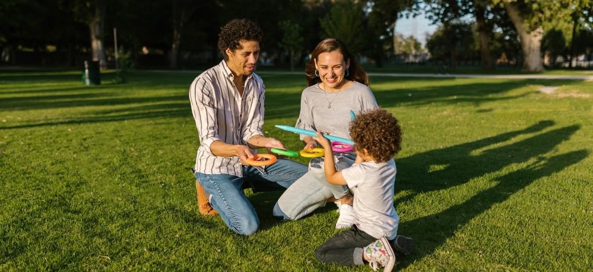 Family playing ring toss together enjoying sunny day in park.