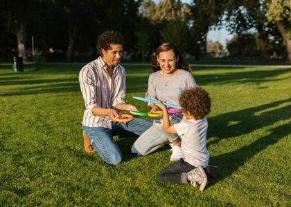 Family playing ring toss together enjoying sunny day in park.